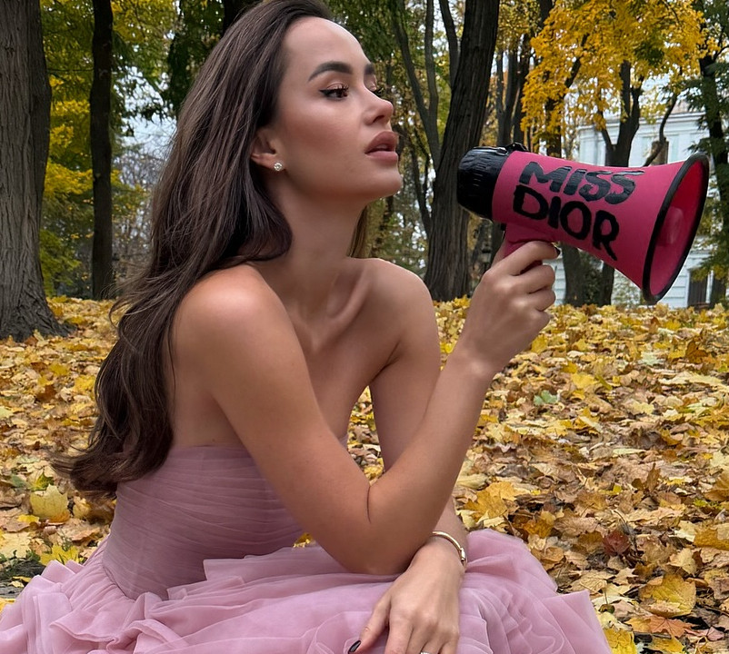 Парфільєва у розкішному платті кольору туманної ружі померзла в осінньому парку з мегафоном. Фото