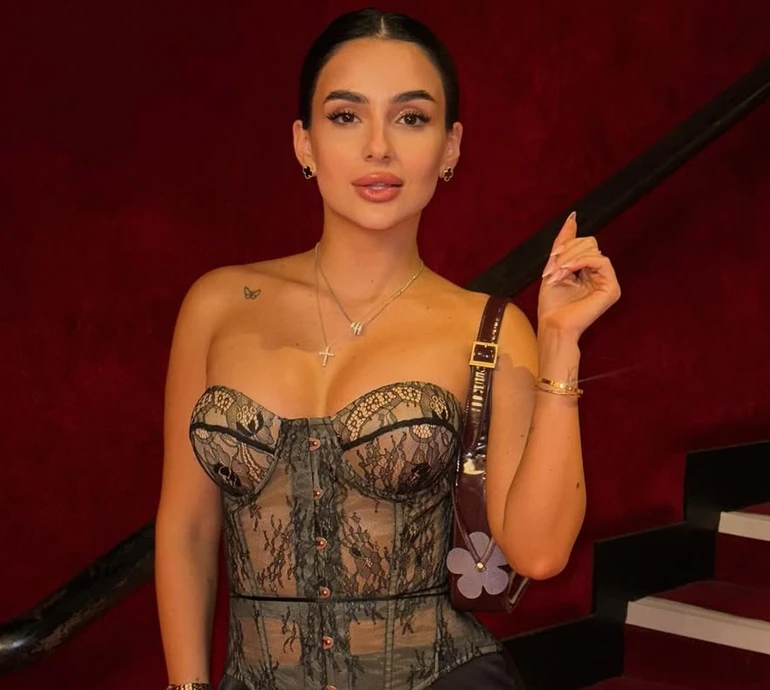 Трінчер у хижому луці з голими плечима поманіжилася на тлі паризьких краєвидів