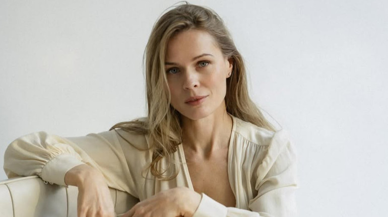 Фреймут у кремовій сукні посиділа босоніж на кріслі для ніжних фото