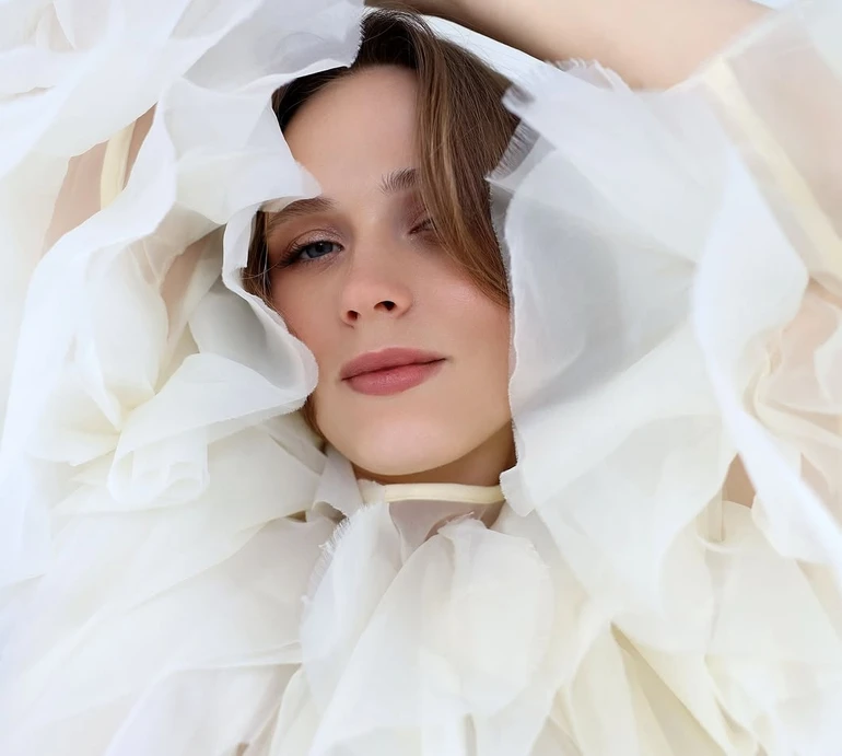 Кошмал у повітряній об'ємній блузі та спідниці граційно оголила стегно на підлозі