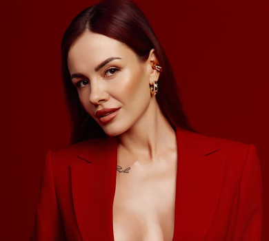 MamaRika у яскравому костюмі з глибоким декольте наробила звабних фото на червоному тлі