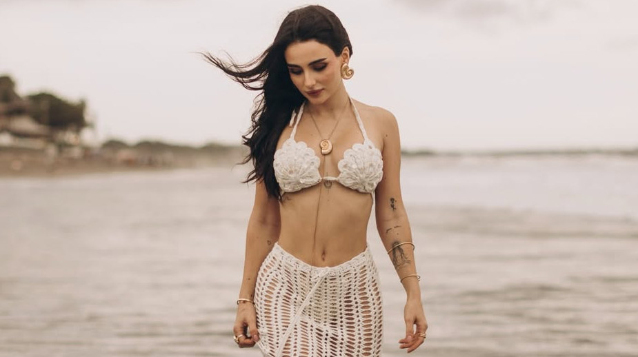 Трінчер з мушлями на грудях і плетених бікіні повигиналася на балійському пляжі. Фото