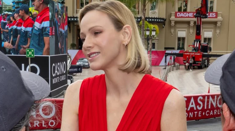 Lady in red: княгиня Монако у плісованому максі приєдналася до чоловіка на презентації автомобілів для рятувальників