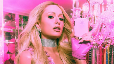 Хілтон у блискучому міні з декольте до талії попозувала на скляному столі для реклами гламурної мобілки