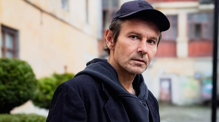 Вакарчук у кепці та стильному худі попозував коло теракотової стіни у місті свого натхнення