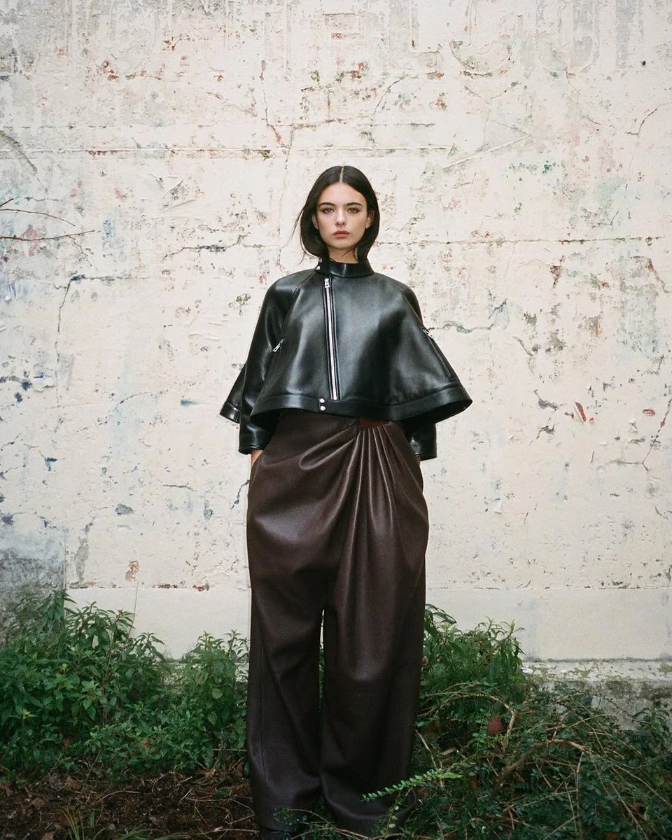 Кассель у шкірянці та широких штанах попозувала біля трави