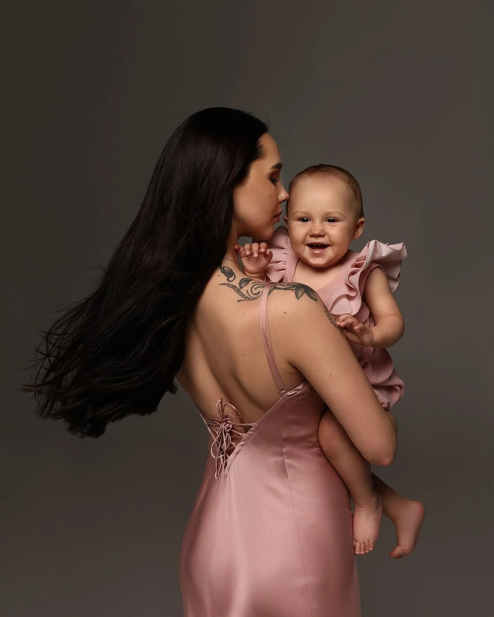 Наталія Татарінцева в обтислій сукенці потримала усміхнену дочку на руках