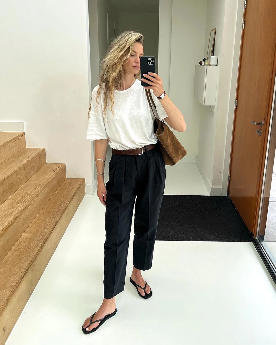 Дівчина у білій футболці, чорних штанах та в'єтнамках