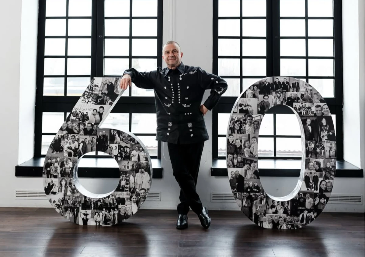 Віктор Павлік у чорному луці попозував коло великої цифри 60 на свій ювілей