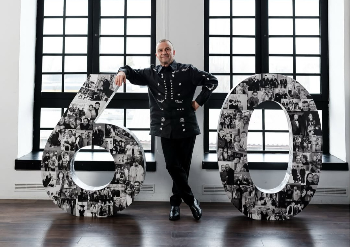 Віктор Павлік у чорному луці попозував коло великої цифри 60 на свій ювілей