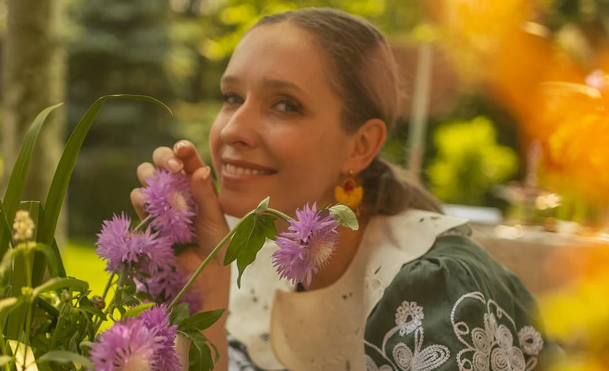 Осадча позує для фото у квітнику