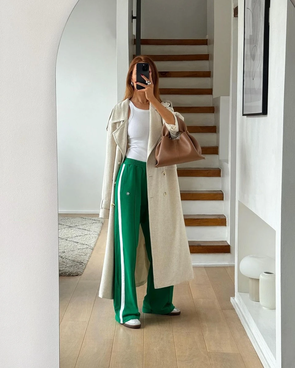 Дівчина у пальто оверсайз і зелених спортивних штанах