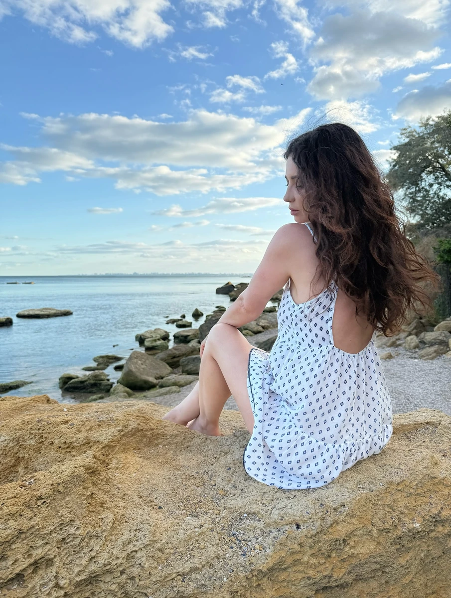 Наталія Дзеньків у білій сукні позує на пляжі