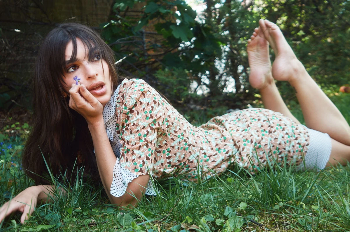 Емілі Ратаковскі в елегантній сукні полежала на траві для фото